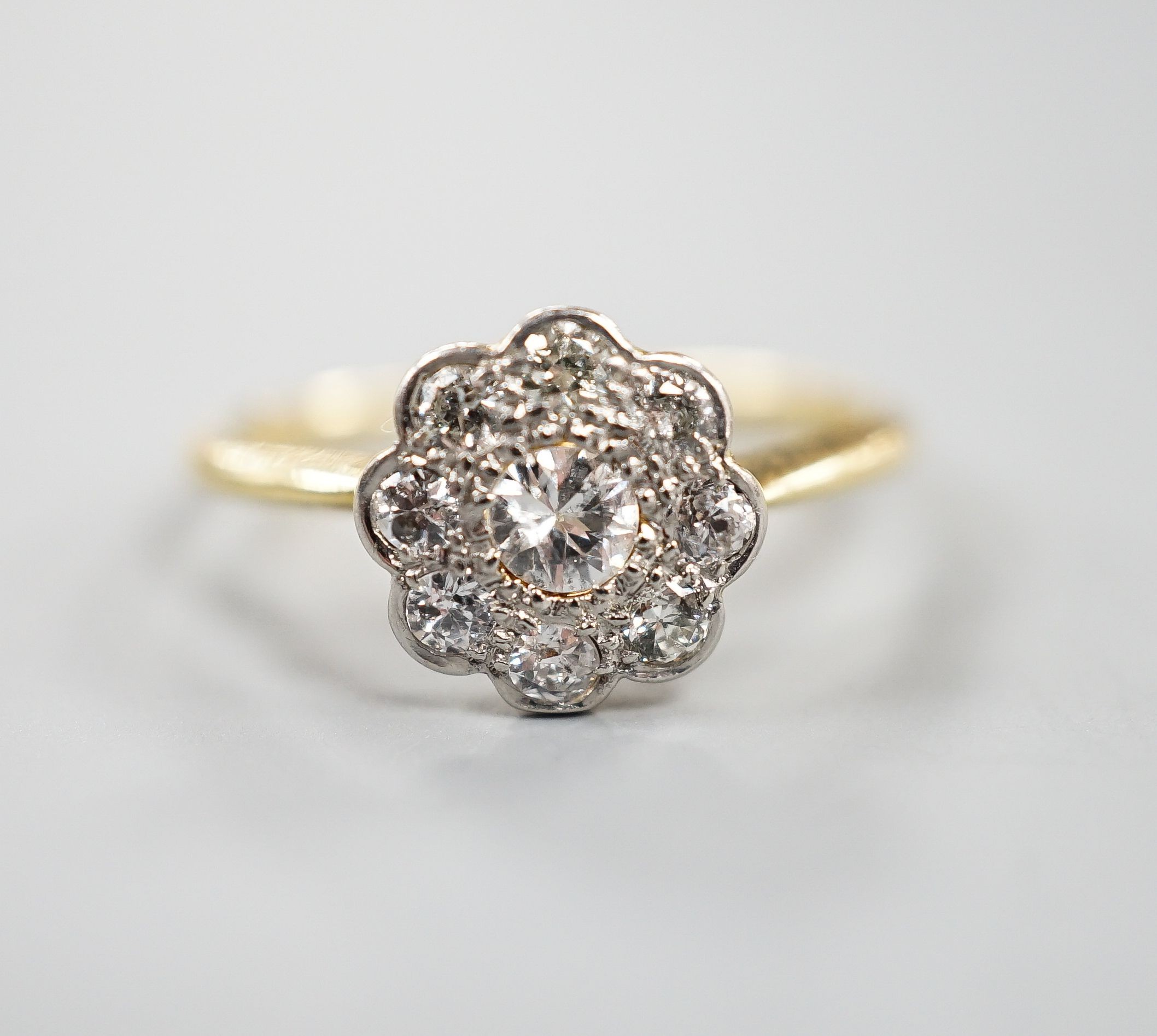 An 18ct, Pt and diamond set flower head cluster ring, size N, gross weight 2.4 grams.